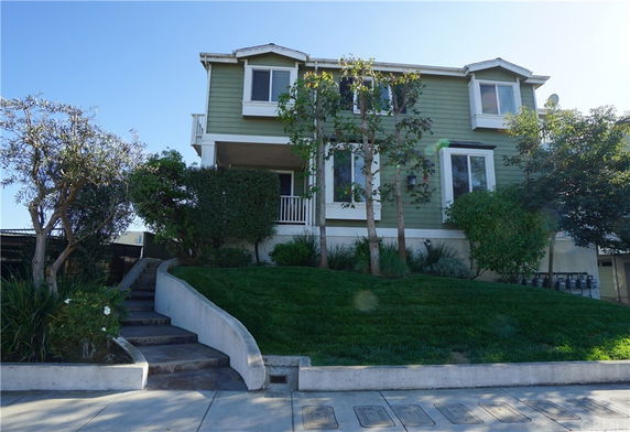 Front view of a two-story house with a green exterior and a small porch.