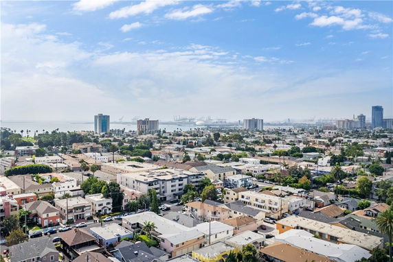 Panoramic view of a cityscape with residential buildings and a view of the coastline in the distance.