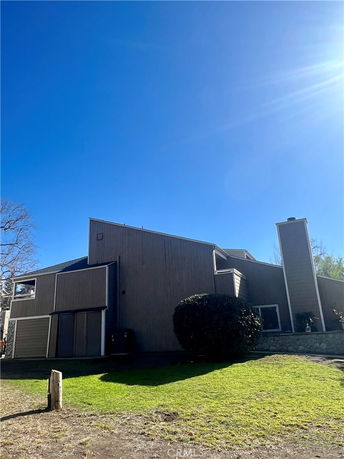 Front view of a multi-story modern house with a chimney and large windows.