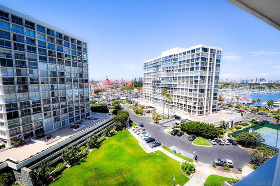 View of tall apartment buildings with a marina and tennis court in the background.