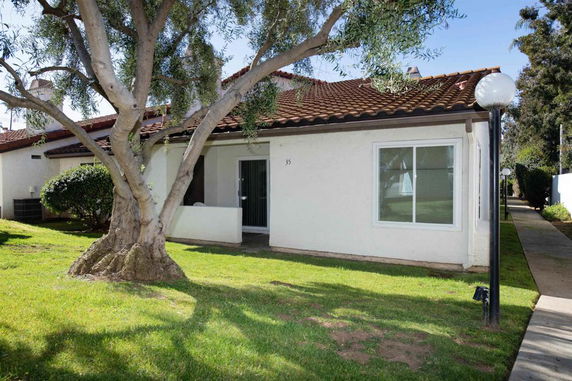 Front view of a single-story house with a tiled roof and patio area.