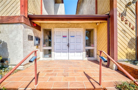 Front view of a building entrance with white double doors and brick steps.