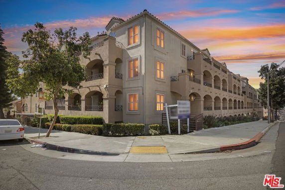 Front view of a multi-story residential building with arched balconies.