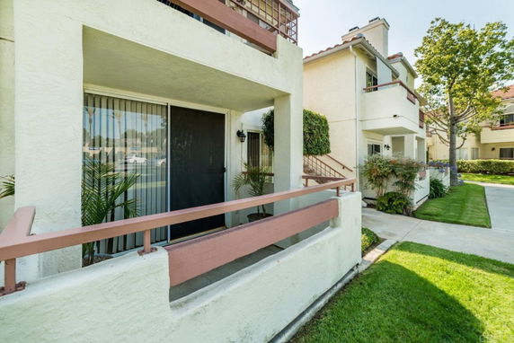 Front view of a multi-story building with balconies and a sliding glass door.