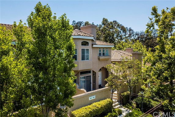 Elevated front view of a two-story house with a tiled roof and arched windows.