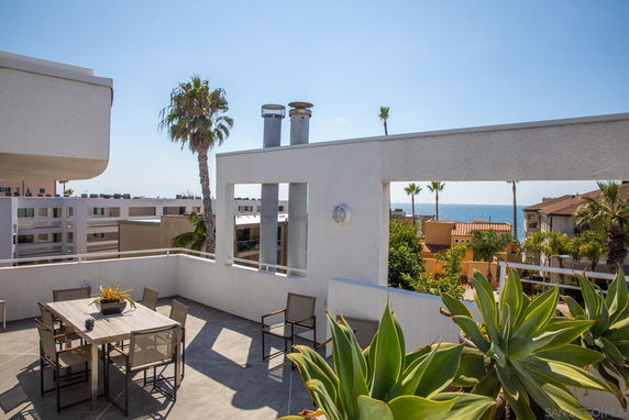 Rooftop patio with seating area overlooking surrounding buildings and the ocean.