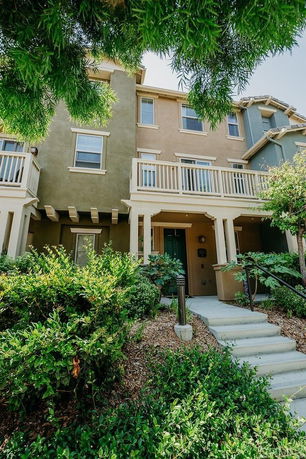 Front view of a multi-story townhouse with a porch and balconies.