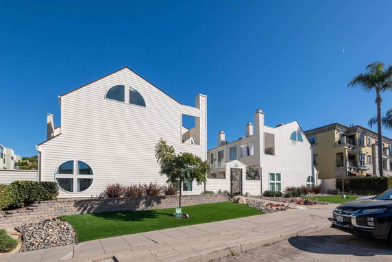 Front view of a modern multi-story building with unique circular windows and light siding.