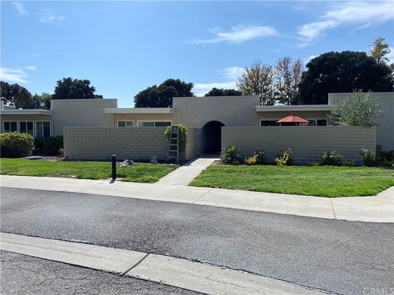 Front view of a single-story house with a wall and entrance path.
