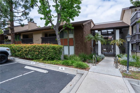 Front view of a two-story residential building with a pathway and parking spaces.