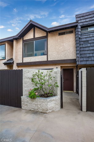 Front view of a two-story house with a fenced entrance and planter.