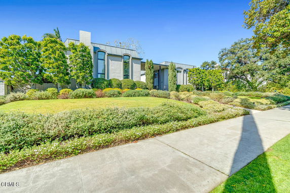 Front view of a modern two-story house with large windows and a garden.