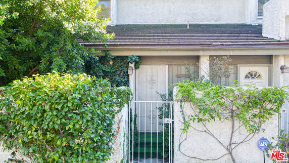 Front view of a house with a gated entrance and greenery