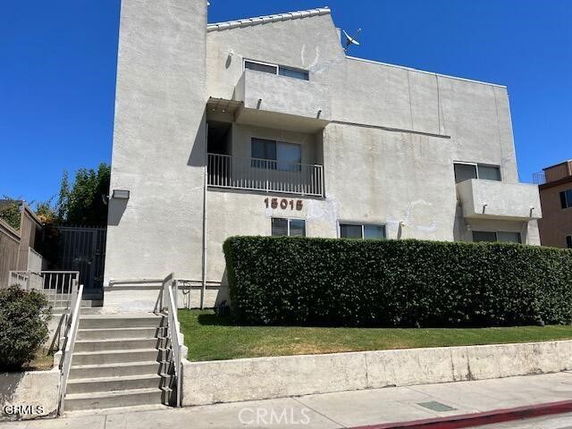 Front view of a multi-story building with balconies and stairs leading to the entrance.