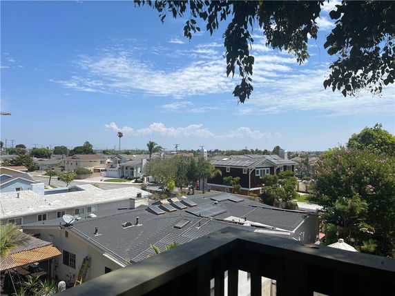 Panoramic view of a residential neighborhood with houses and trees under a blue sky.