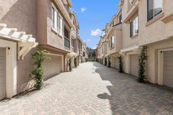 Outdoor parking area between rows of residential buildings with garages.