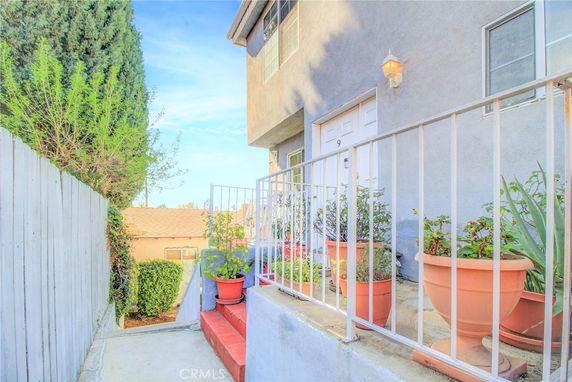 Front view of a house entrance with potted plants and a railing.