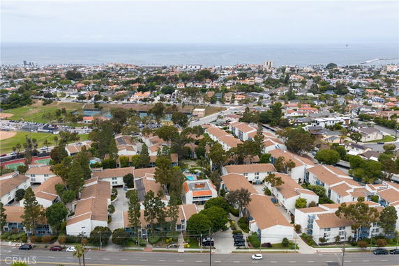 Aerial view of a residential neighborhood with multiple buildings, roads, and the ocean in the background.