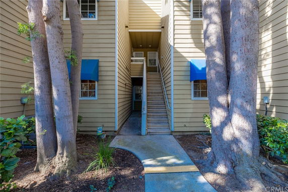 Front view of a multi-story building with a central staircase and blue window awnings.