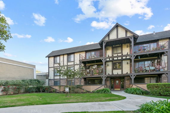 Front view of a three-story building with a rustic design featuring wooden beams and balconies.