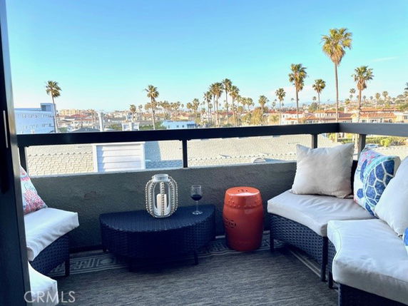 Balcony area with seating overlooking palm trees and distant buildings.