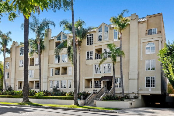 Front view of a multi-story residential building with palm trees in front.