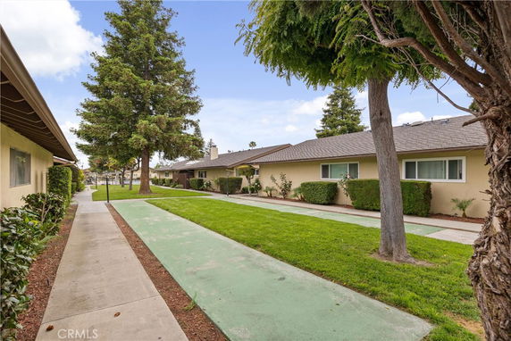 Side view of a row of single-story houses with a walkway and greenery.