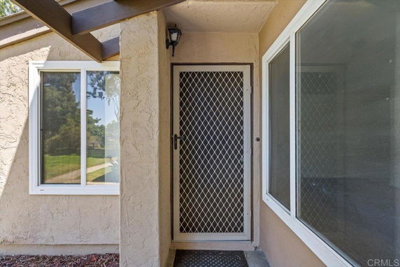 Front view of a house entrance with a security screen door and windows.