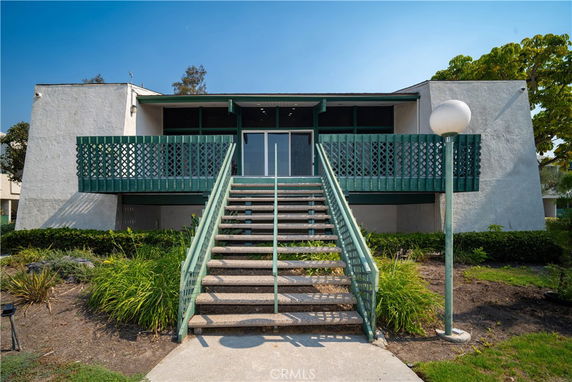 Front view of a building with a staircase leading to a balcony entrance.
