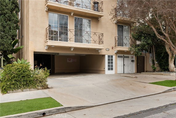 Front view of a multi-story building with balconies and a driveway.