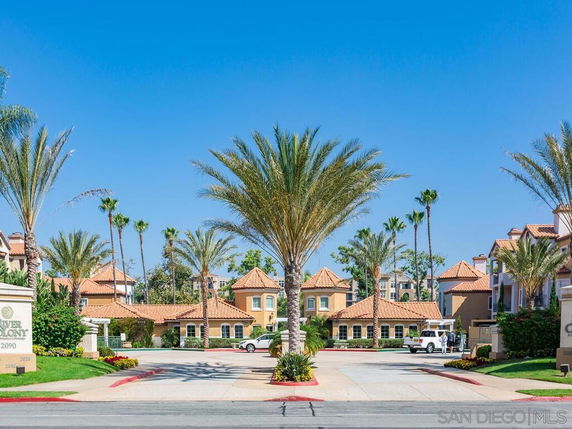 Front view of a residential complex with palm trees and tiled roofs.