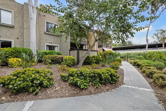 Front view of a multi-story residential building with a pathway and landscaping.