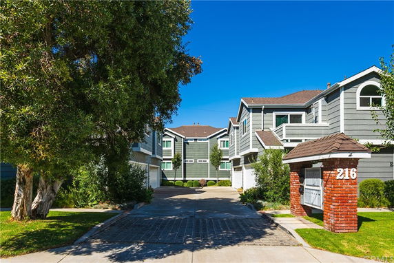 Front view of a multi-story residential building with a driveway and brick mailbox structure.