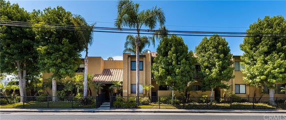 Front view of a multi-story building with a tiled roof and surrounded by tall trees.