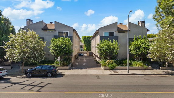 Front view of a two-story residential building with symmetrical design and landscaped entrance.