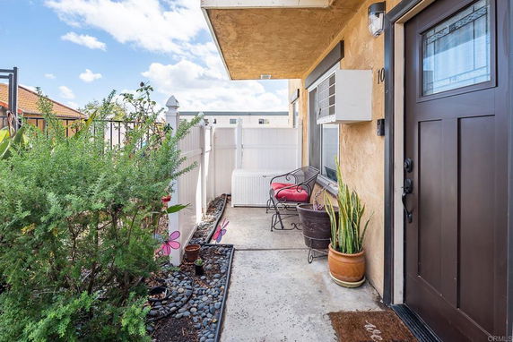 Front view of a house entrance with a small patio area and potted plants.
