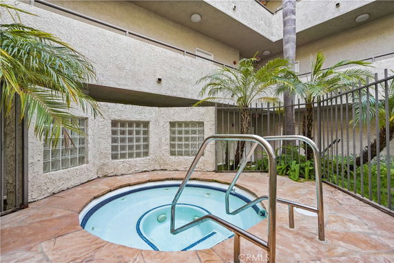Indoor jacuzzi area in a building with surrounding plants and a glass block wall.