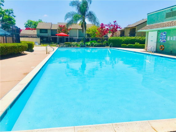Outdoor swimming pool with adjacent building and surrounding fence.