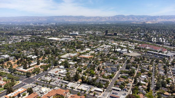 Aerial view of an urban area with a mix of residential and commercial buildings and distant mountains.