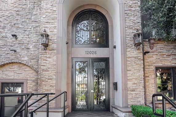 Front view of a building with a stone exterior and ornate metal entrance doors.