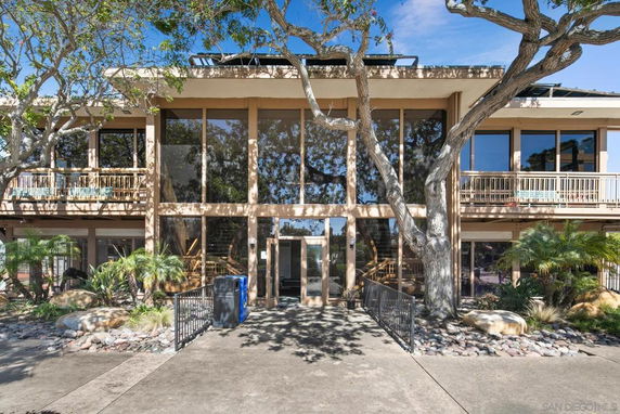 Front view of a two-story building with large glass windows and surrounding trees.