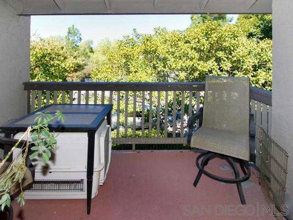 Outdoor patio area with a table and chair overlooking greenery.
