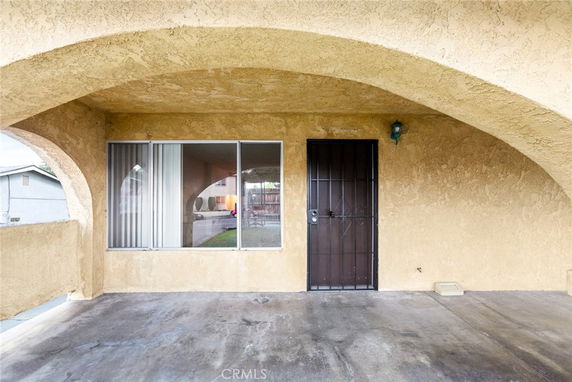 Front view of a building with arched entrance and a window beside a metal door.