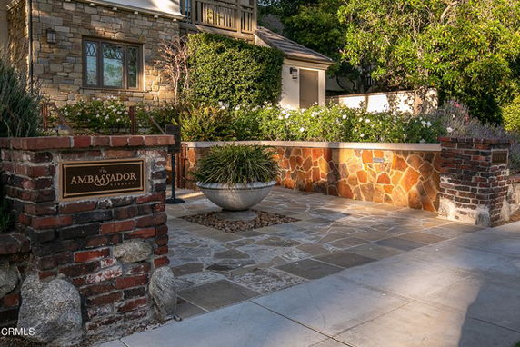 Front view of a building with stone and brick facade, featuring a walkway and landscaping.