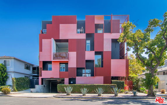 Front view of a modern multi-story building with a red and black geometric facade.