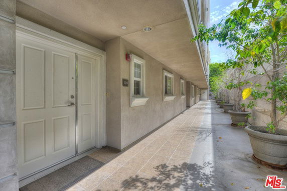 Exterior walkway of an apartment building with doors and windows.