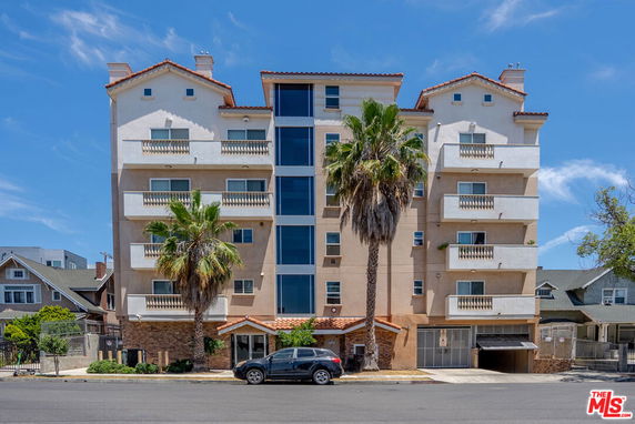 Front view of a multi-story residential building with balconies and a central entrance.