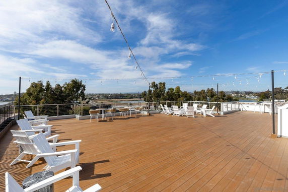 Rooftop deck with chairs and a panoramic view of greenery and distant cityscape.