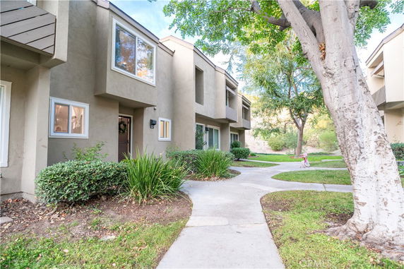 Front view of a row of two-story townhouses with landscaped paths and greenery.