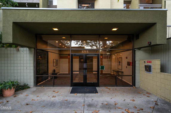 Front view of a building entrance with glass doors and surrounding structure.